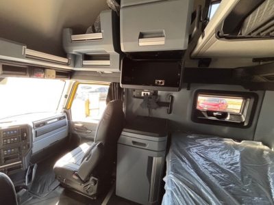 Interior of new 2026 Mack PR64T76H sleeper cab showing driver seat, overhead storage, and dashboard with cabinetry.