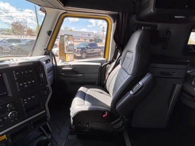 Truck cab interior of a 2026 Mack PR64T76H showing driver seat, dashboard, and window with reflection.