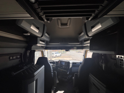 Cab interior of a new 2026 Mack PR64T76H truck showing cockpit with dashboard, overhead storage, and seats.