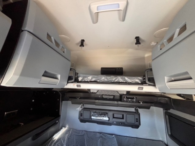 Mack PR64T76H sleeper cab interior showing overhead storage compartments and controls, with a view of the dash and center console area.