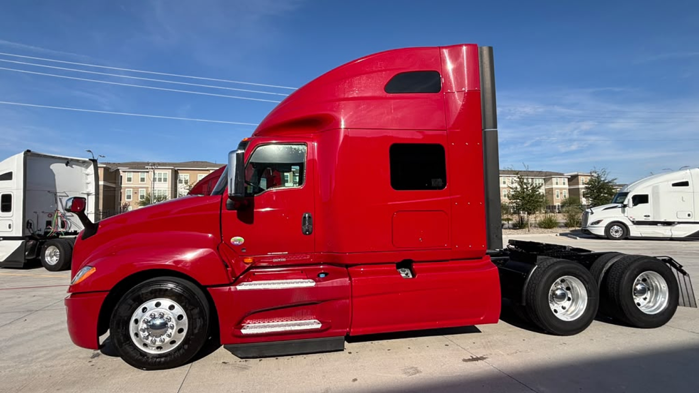 Truck side view of a red 2022 International LT625 sleeper tractor showing the cab and rear axles.