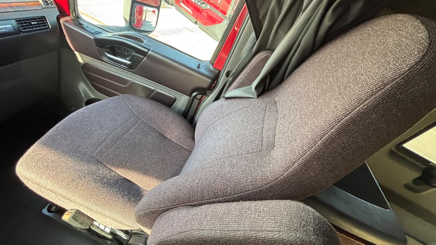 Cab interior of a used 2022 International LT625 showing driver seat and part of the door panel.
