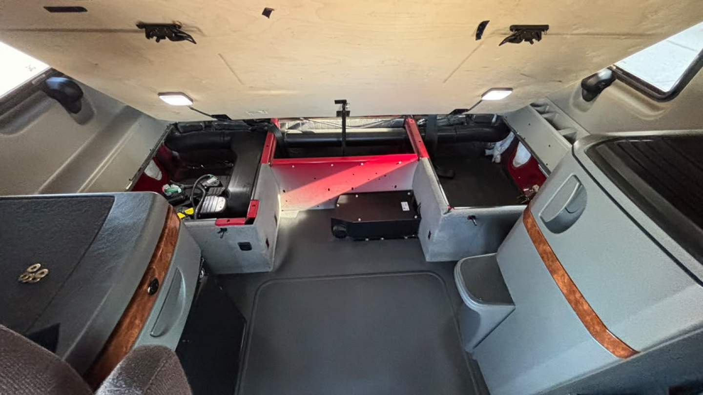 Truck cab interior with sleeper area and storage compartments, cargo area visible from behind.