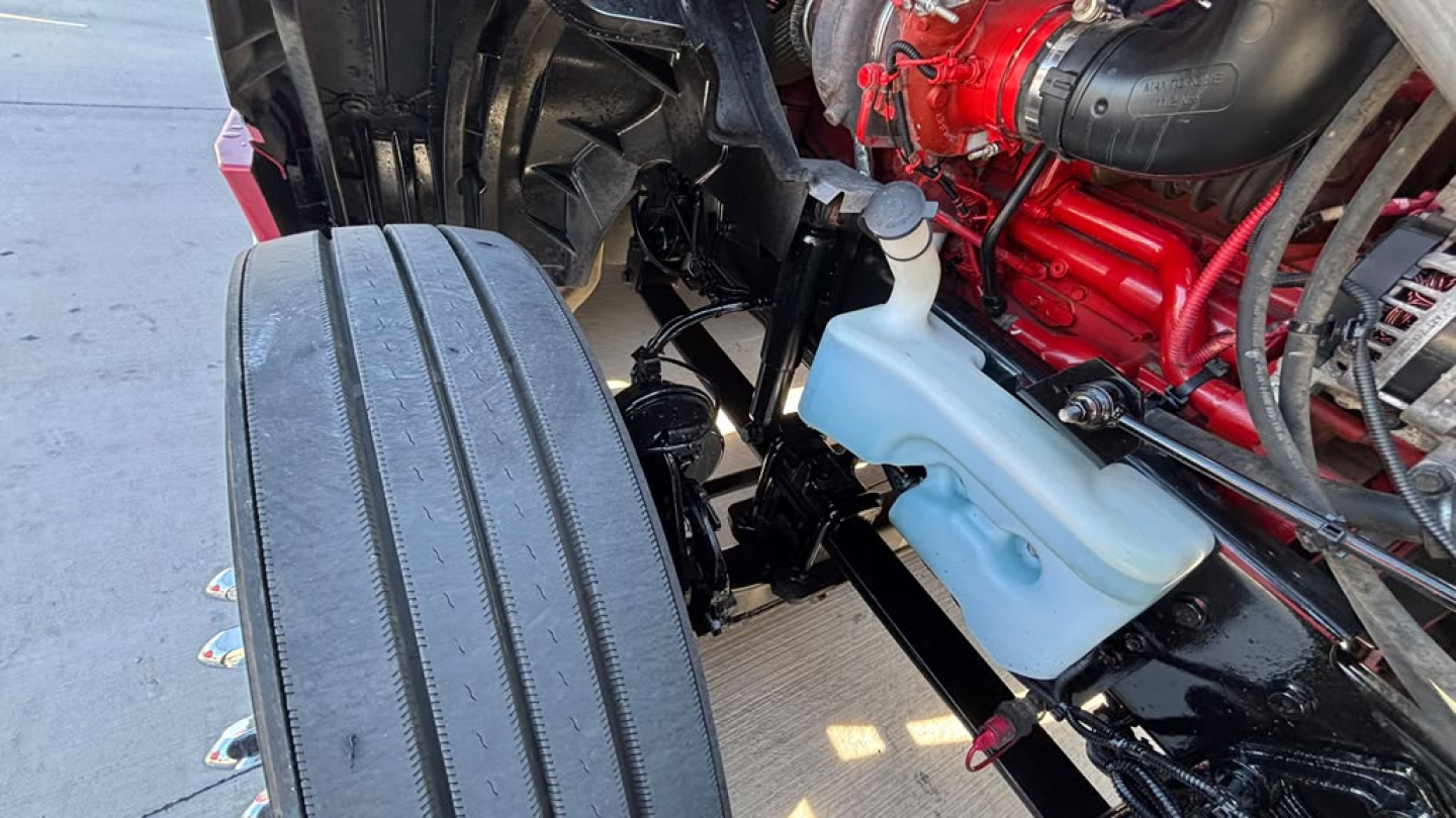 Engine bay and front chassis of a 2022 International LT625 sleeper showing coolant reservoir and engine components.