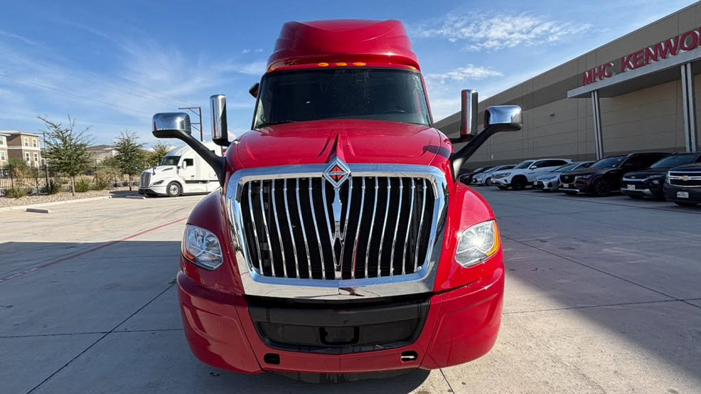 Truck front view of red 2022 International LT625 with chrome grille and chrome accents in a dealership lot.