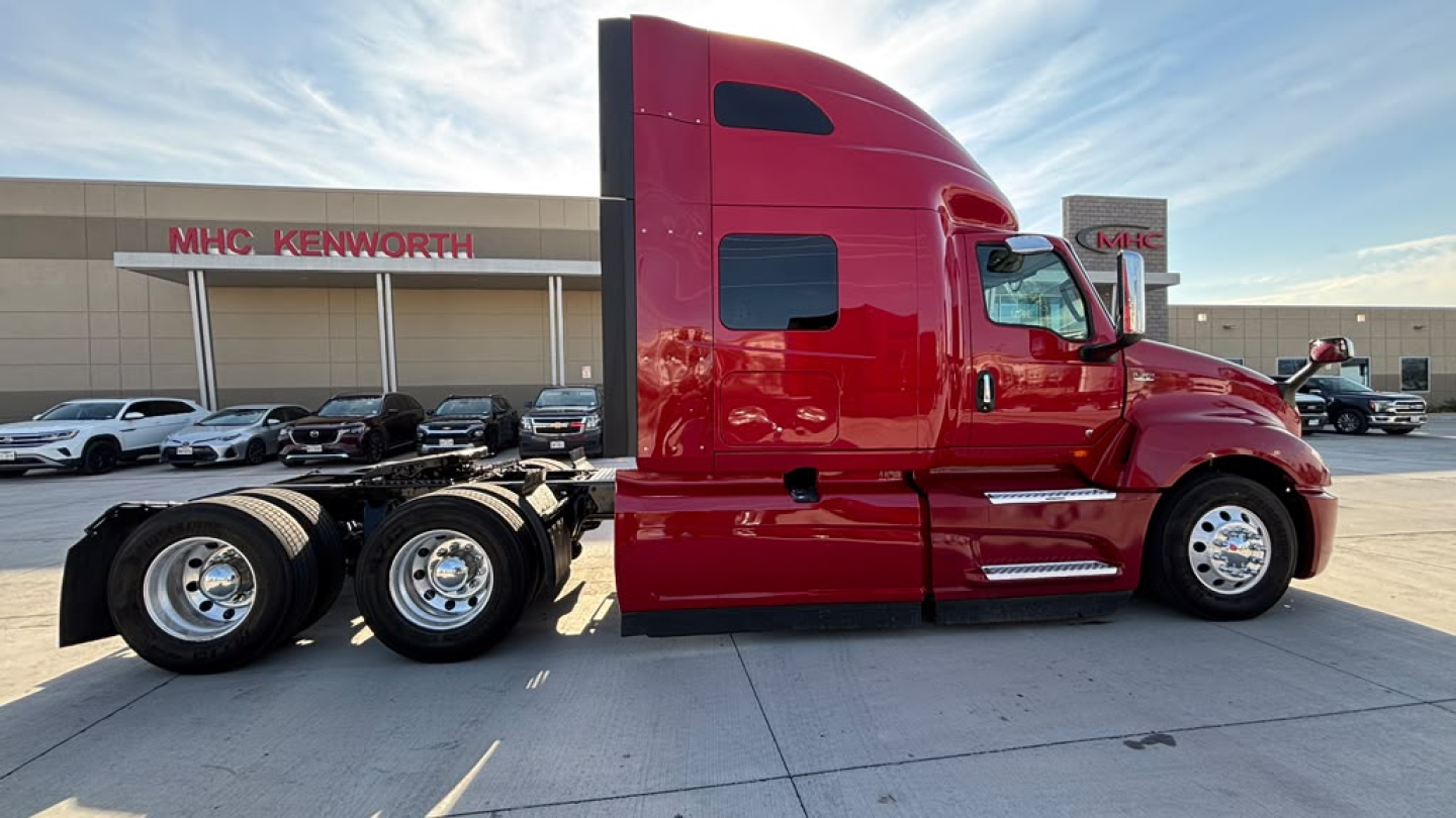 International LT625 tractor unit side view showing red sleeper cab and dual rear axles with chrome wheels.