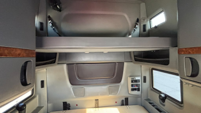 Interiors of a sleeper cab showing overhead bunk, side storage cabinets, window, and control panel in a 2022 International LT625 truck.