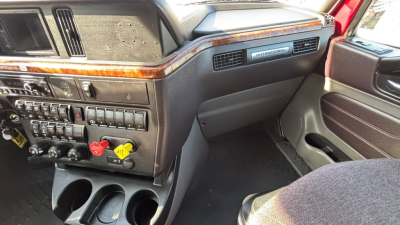 Dashboard and center console of a 2022 International LT625 truck cab with wood trim, controls, and cup holders.