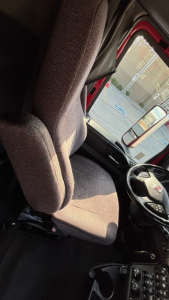 Interior close-up of a truck cab seat and steering wheel from a 2022 International LT625 showing fabric-covered driver seat and dashboard controls.