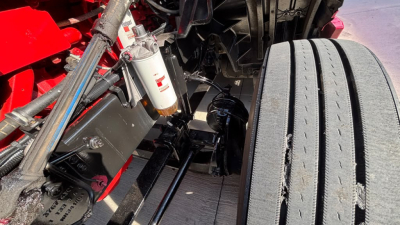 Truck front suspension and air filter visible in engine bay of 2022 International LT625, with stabilizer bars, hoses, and dual rear tires partially shown.