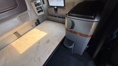 Interior sleeper cab floor and side console of a 2022 International LT625 truck showing light-colored sleeper area with wear marks and a storage console.
