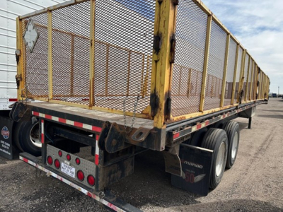 Manac closed tandem air ride steel flatbed trailer with mesh sides, viewed from rear-right, showing dual rear axles and white reflective safety markings.