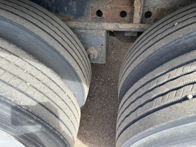 Flatbed trailer view of twin rear wheels and undercarriage showing wheels and frame connections.