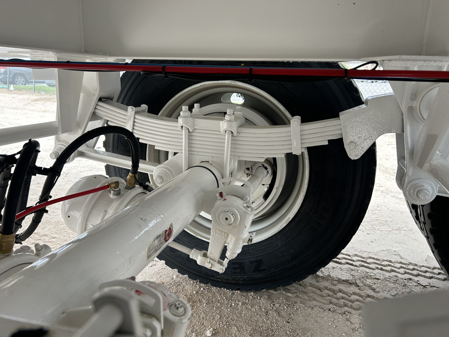 Rear suspension and wheel of a new Troxell vacuum trailer showing leaf spring suspension, axle, tire, and hitch components.