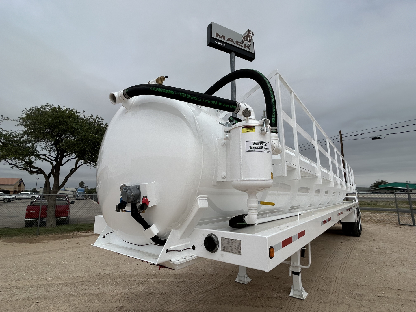 Truck trailer showing white 130BBL vacuum tank with hoses and rear valve and taillights