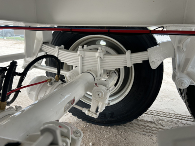 Rear suspension and wheel of a new Troxell vacuum trailer showing leaf spring suspension, axle, tire, and hitch components.