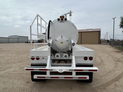 Rear view of a white vacuum trailer with a large cylindrical tank, rear lights, safety rails, and a rear bumper.