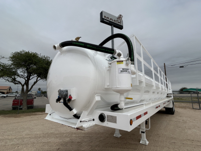 Truck trailer showing white 130BBL vacuum tank with hoses and rear valve and taillights