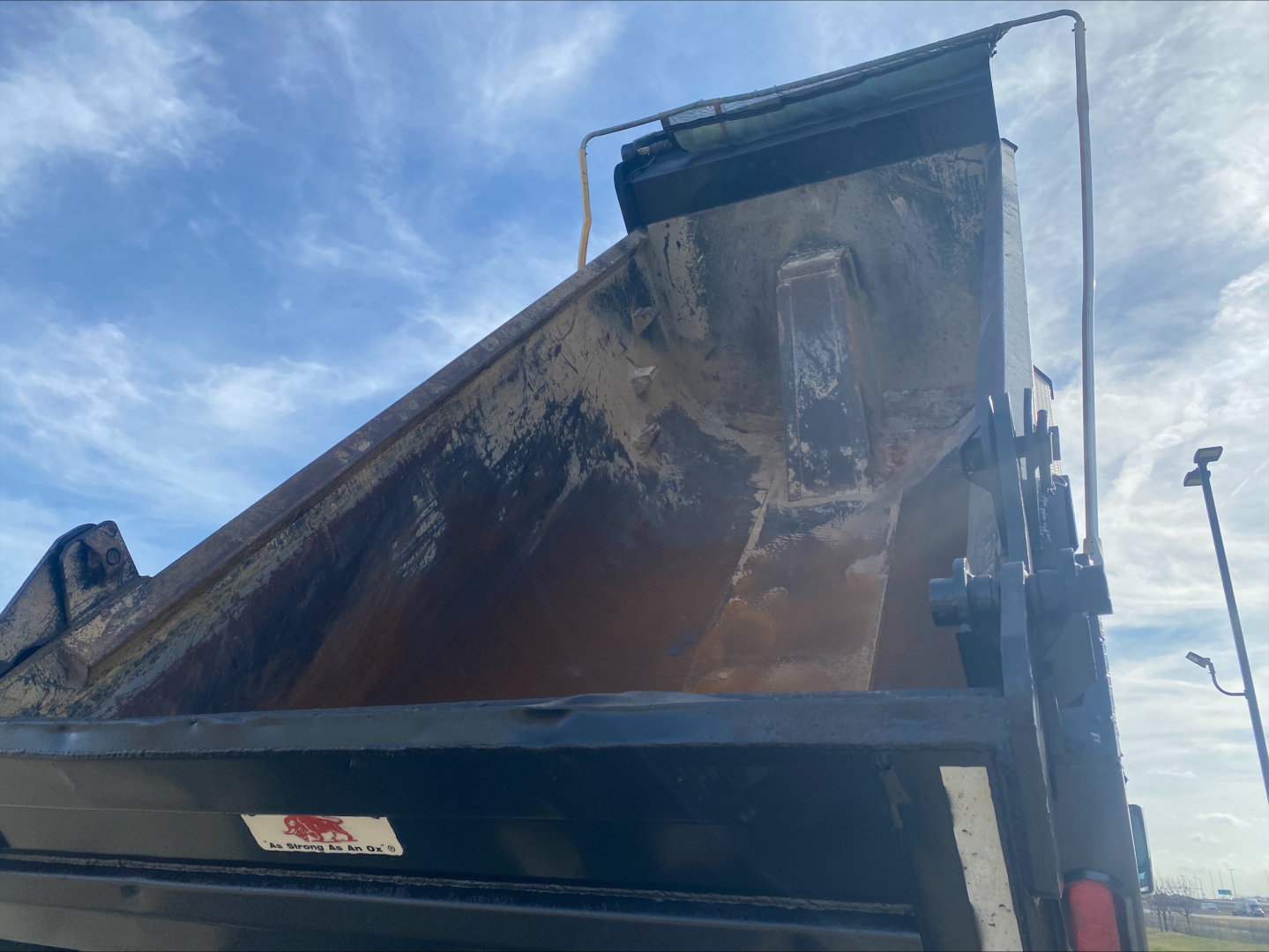 Dump truck bed with dirt and hydraulic lift, Volvo-style dump body visible.