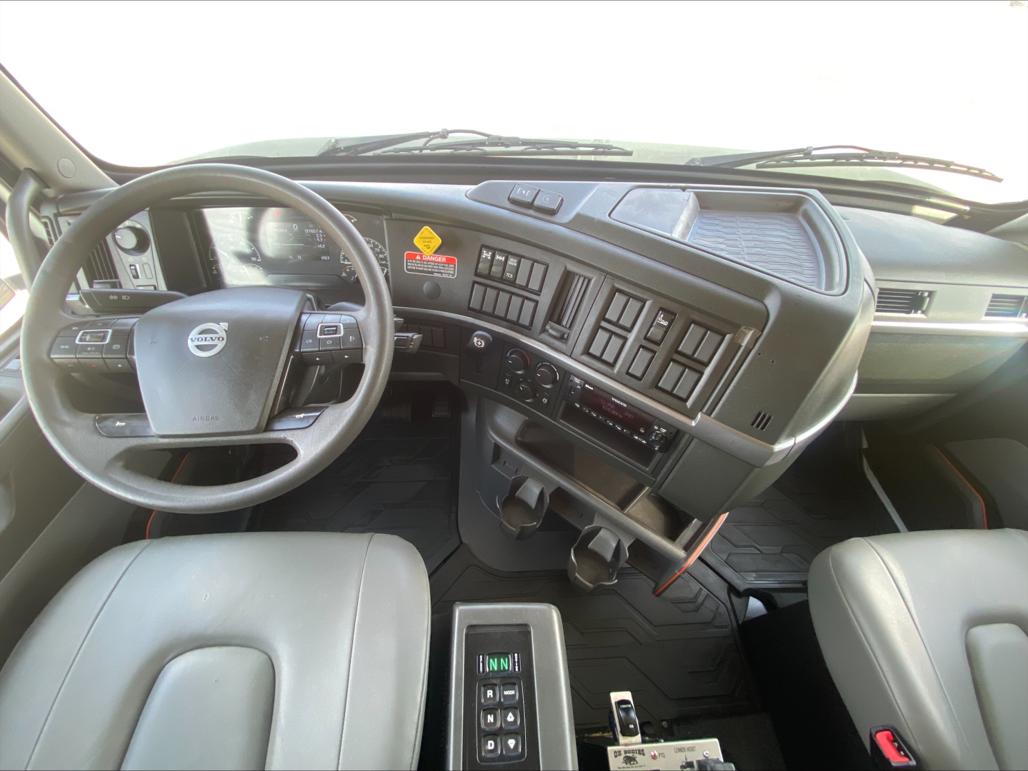Volvo VHD84F200 truck cabin interior showing steering wheel, dashboard with controls, center console and gear selector.