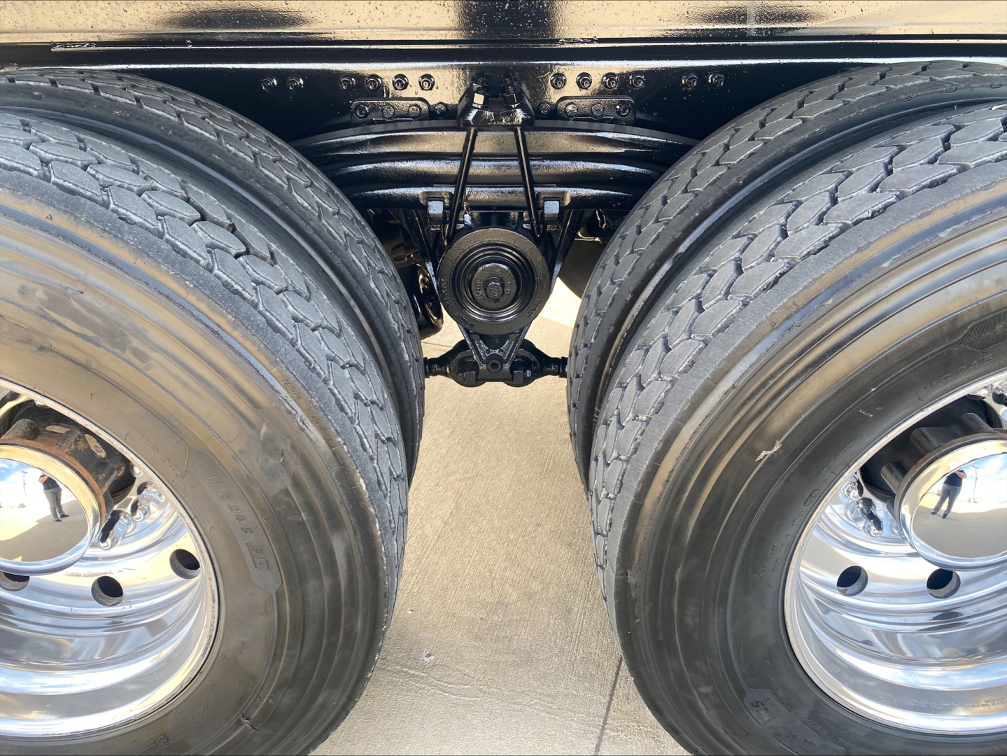 Rear dual tandem axle of a Volvo VHD84F200 dump truck showing suspension, driveshaft, and dual wheels with chrome rims.