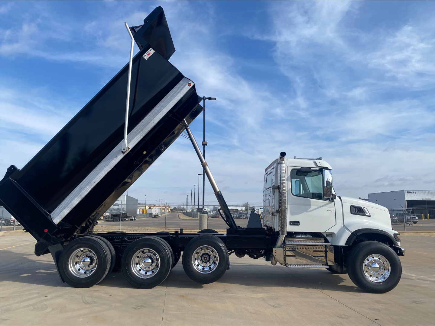 Volvo VHD84F200 dump truck side view showing hydraulic dump bed raised and multiple rear axles.