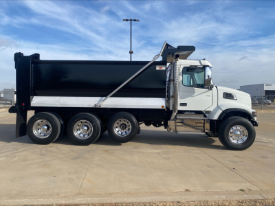 Dump truck with black dump body showing side panels and chrome wheels; no visible brand text on cab; long wheelbase with seven tires; white cab and black bed.