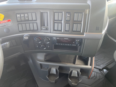 Volvo truck dashboard with multiple switches and climate controls, cigarette lighter area, and cup holders visible in the center console.
