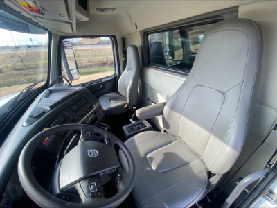 Cab interior of a Volvo VHD84F200 dump truck showing steering wheel, driver seat, and dashboard with gray upholstery.