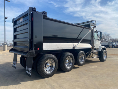 Volvo VHD84F200 dump truck in-service three-axle rear with black dump body, chrome wheels, side step, and hydraulic tailgate in a dealership lot.