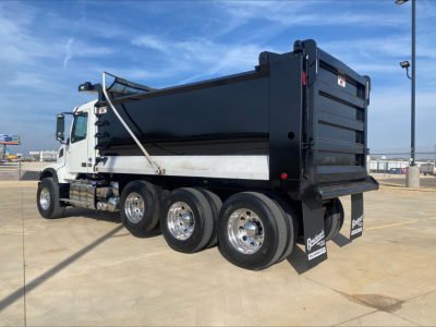 Dump truck side and rear view showing multiple axles, black dump bed, white cab, chrome wheels, and mud flaps.