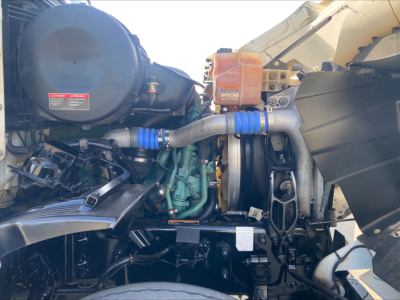 Volvo VHD84F200 dump truck engine bay showing turbochargers and intercooler hoses, blue silicone hose couplers, coolant reservoir, and engine block with surrounding components.