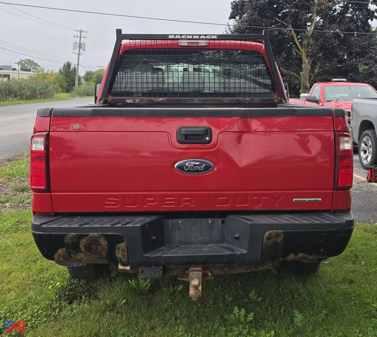 Ford F-250 Super Duty rear view showing tailgate with embossed SUPER DUTY and tow hitch, red crew cab pickup with back window and metal bumper.