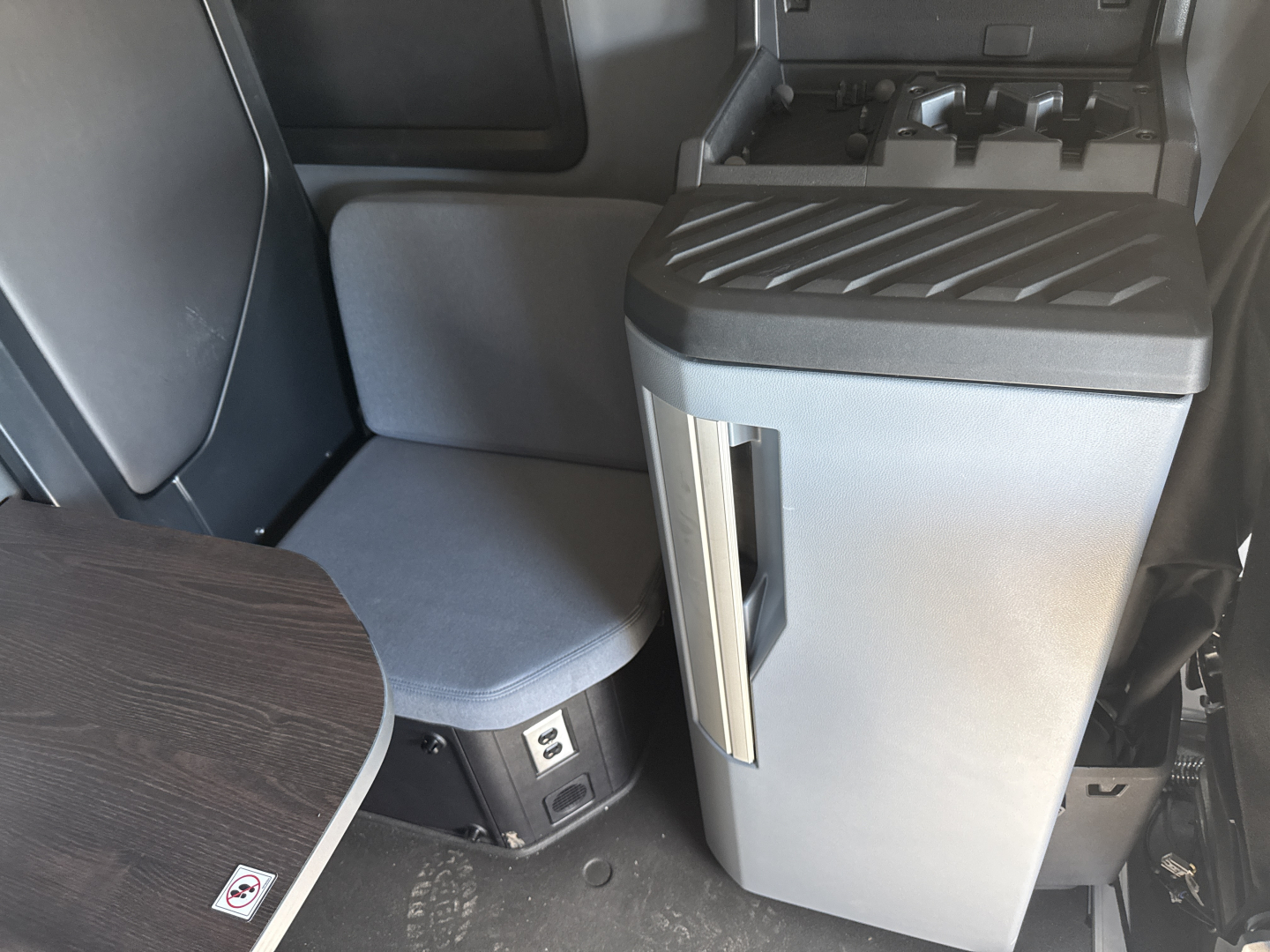Cab interior of a 2026 Mack PR64T76H showcasing a swivel seat with gray fabric, center console with storage, and control panel area.