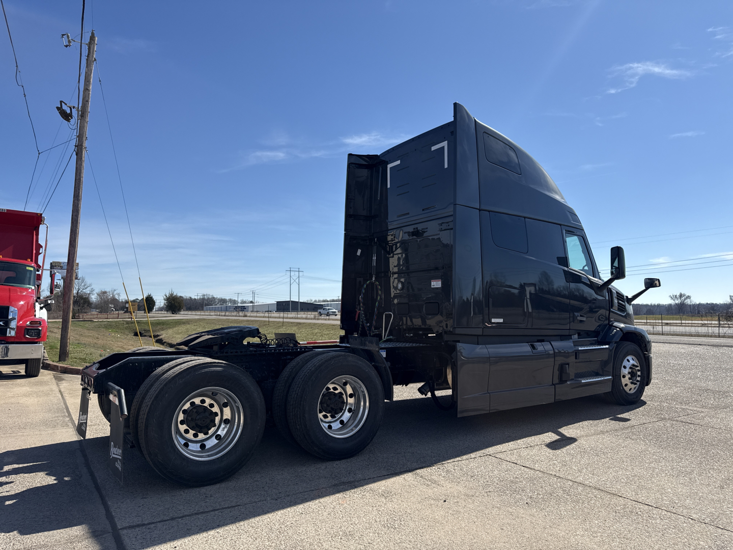 Black Mack PR64T76H semi-truck tractor in a parking lot, side view showing the sleeper cab with number 1, dual rear axles, chrome wheels, and fuel/air components; no visible warning labels readable.