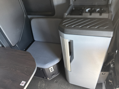 Cab interior of a 2026 Mack PR64T76H showcasing a swivel seat with gray fabric, center console with storage, and control panel area.