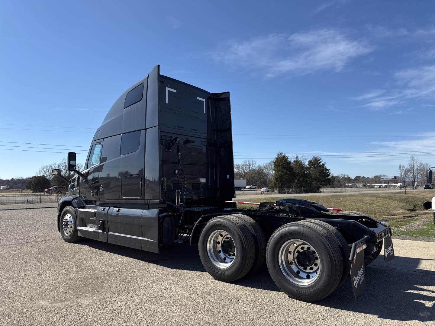 Mack PR64T76H conventional sleeper truck, side rear view showing twin rear axles and chassis, with glossy black paint and high cab roof.