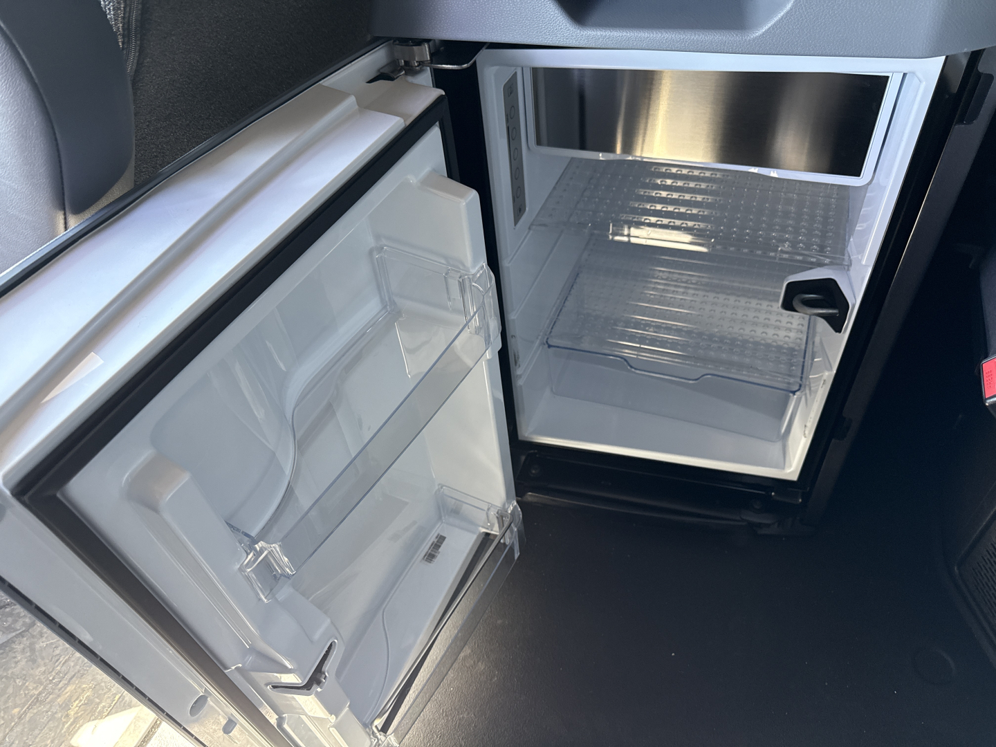Fridge/freezer in a Mack PR64T76H cab interior showing open mini refrigerator/freezer with shelves and door compartments.