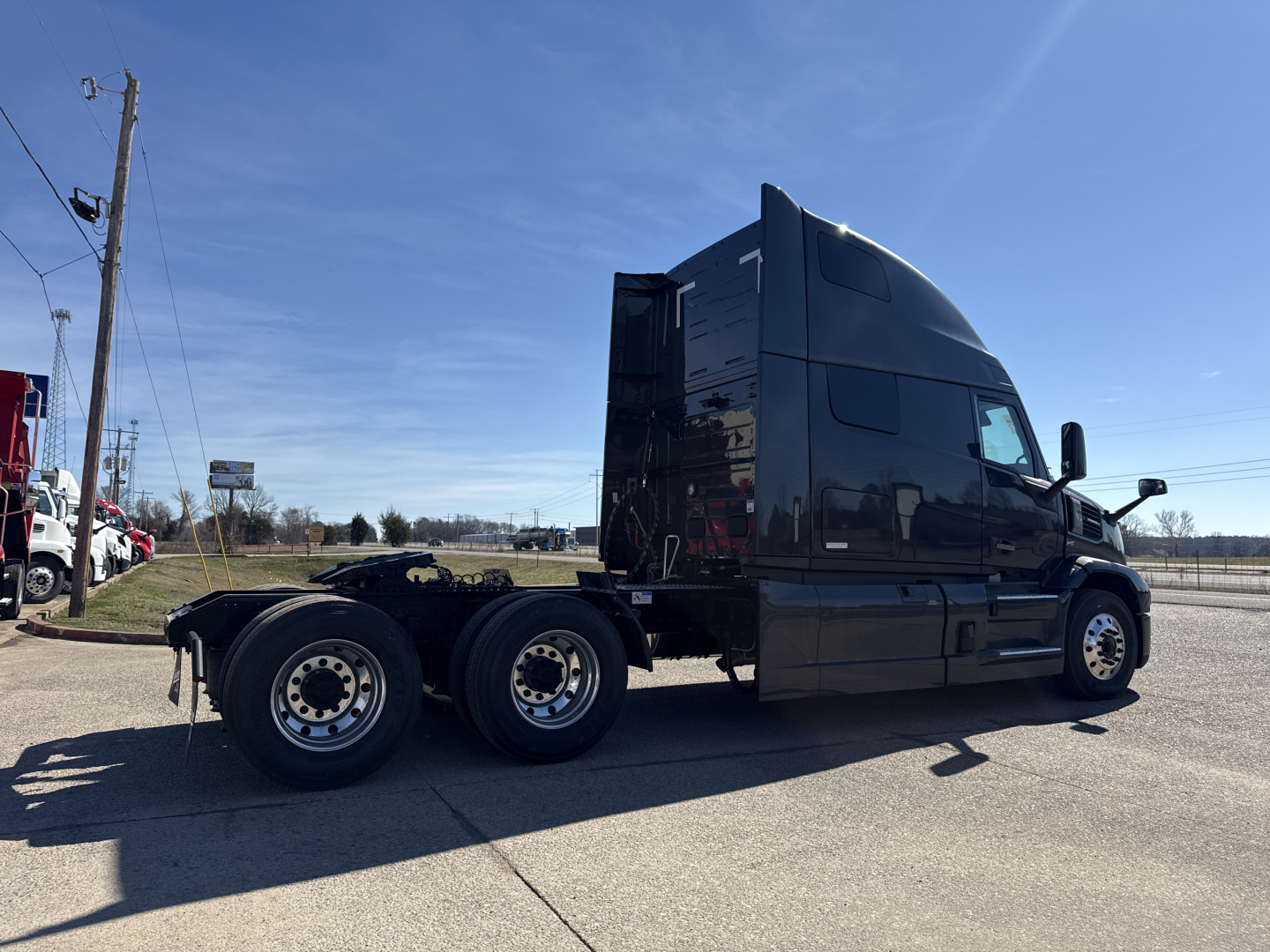 Mack PR64T76H conventional sleeper truck side view showing tandem rear axles, black cab, and aerodynamic sleeper, with clear weather.