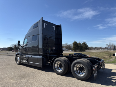 Mack PR64T76H conventional sleeper truck, side rear view showing twin rear axles and chassis, with glossy black paint and high cab roof.