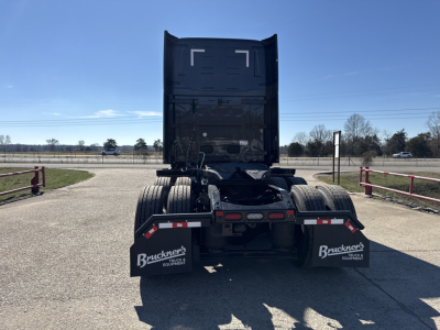 Rear view of a new Mack PR64T76H conventional sleeper truck showing rear chassis, fifth-wheel, and dual rear tires with mud flaps and reflective tape.