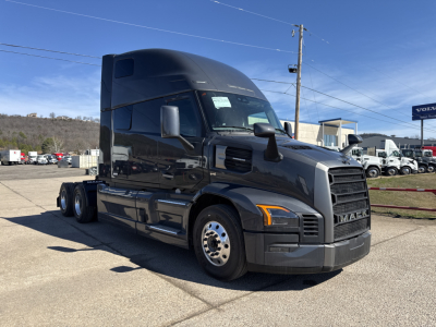 Truck cab of 2026 Mack PR64T76H sleeper with black exterior, side mirror, and fuel tanks visible on a dealership lot.