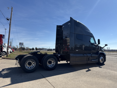 Mack PR64T76H conventional sleeper truck side view showing tandem rear axles, black cab, and aerodynamic sleeper, with clear weather.