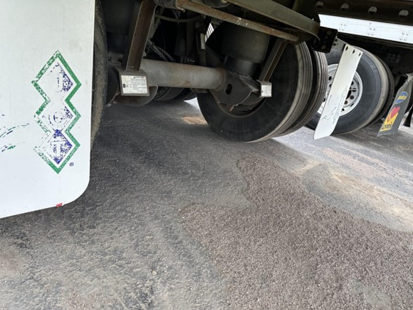 Trailer underside showing axles, suspension, and wheel hub of a 2015 Utility 3000R reefer trailer; visible components include wheel, multiple axles, and part of refrigeration unit mounting.