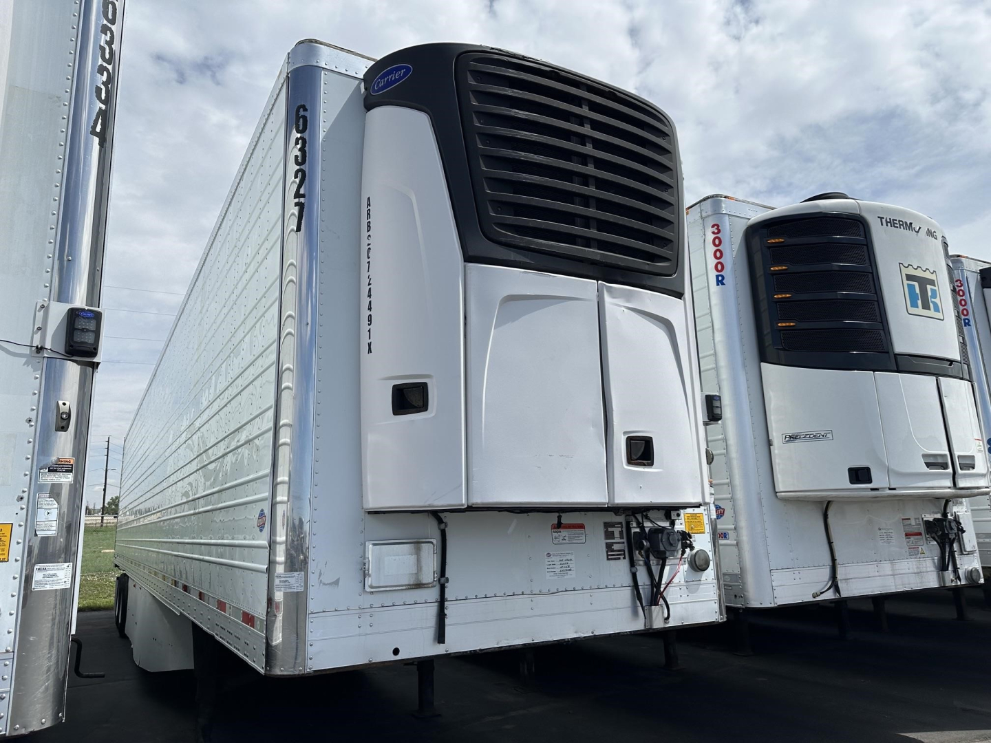 Utility 3000R trailer with Reefer unit showing front refrigeration unit and side panel, white with black front grill, parked among similar trailers.