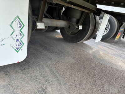 Trailer underside showing axles, suspension, and wheel hub of a 2015 Utility 3000R reefer trailer; visible components include wheel, multiple axles, and part of refrigeration unit mounting.