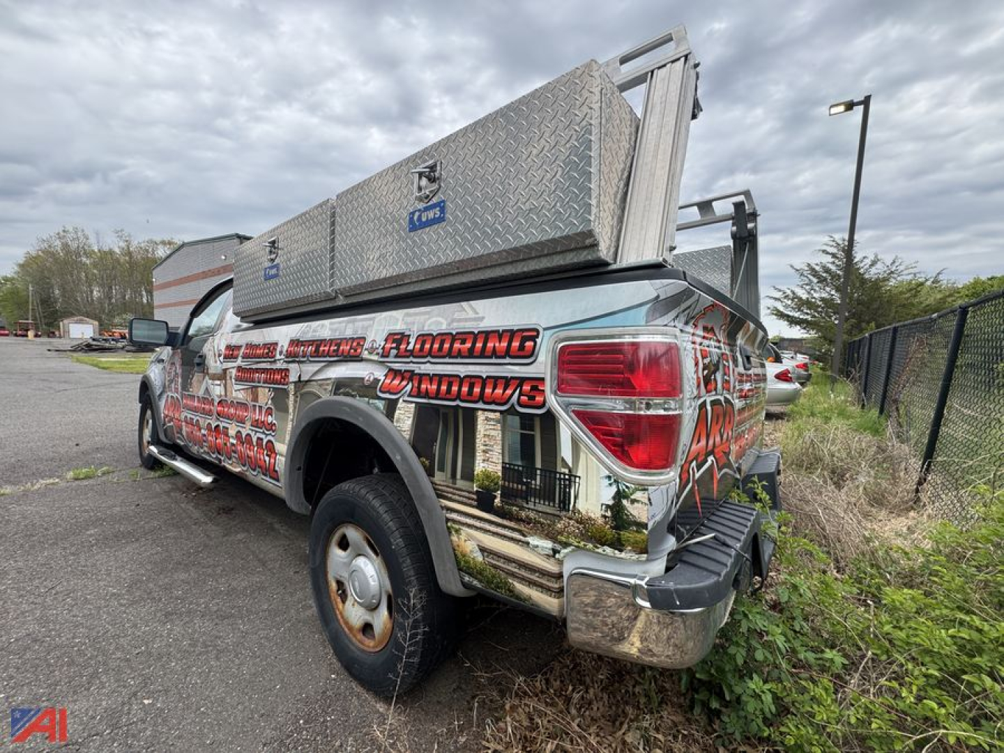 Ford F-150 pickup truck with diamond plate storage box on bed and custom graphics along the side and rear.