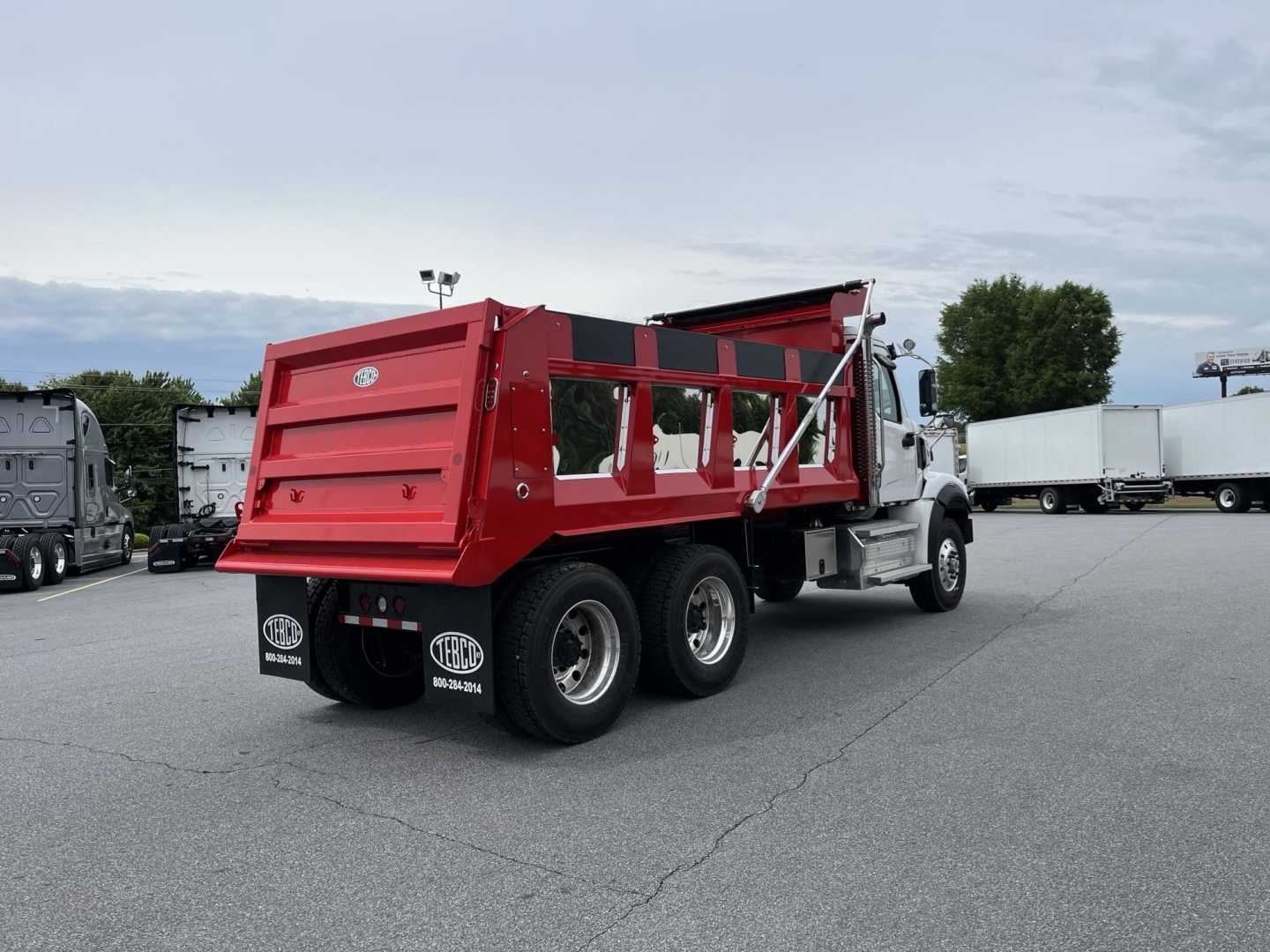 Dump truck with red dump bed and white cab, rear three-axle configuration, parked in lot. Visible text includes BOSS logos on mudflaps and truck side.