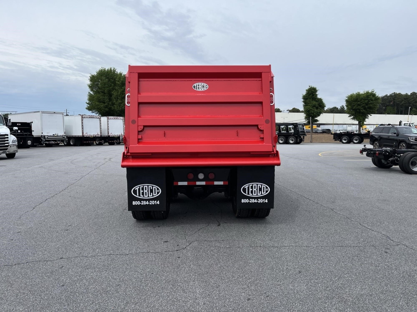 Rear view of red Western Star dump truck bed with TEBC logos on mud flaps, showing the tailgate and safety reflectors.