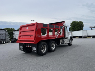 Dump truck with red dump bed and white cab, rear three-axle configuration, parked in lot. Visible text includes BOSS logos on mudflaps and truck side.